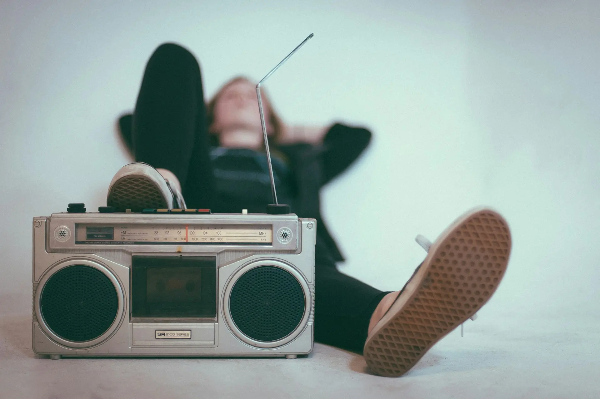 Une femme allongée avec un pied sur un vieux poste de radio